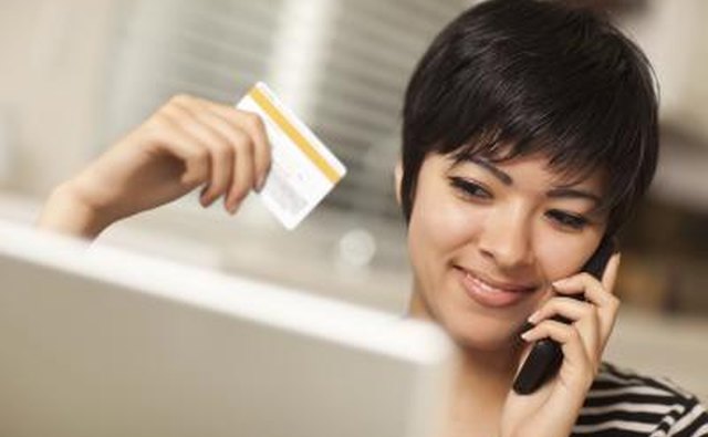 Женщина по телефону держит кредитную карту